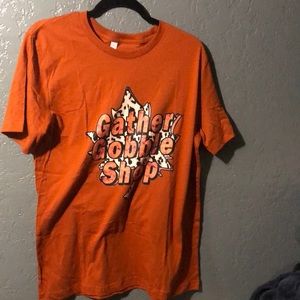 L tee with “Gather Gobble Shop” on it.